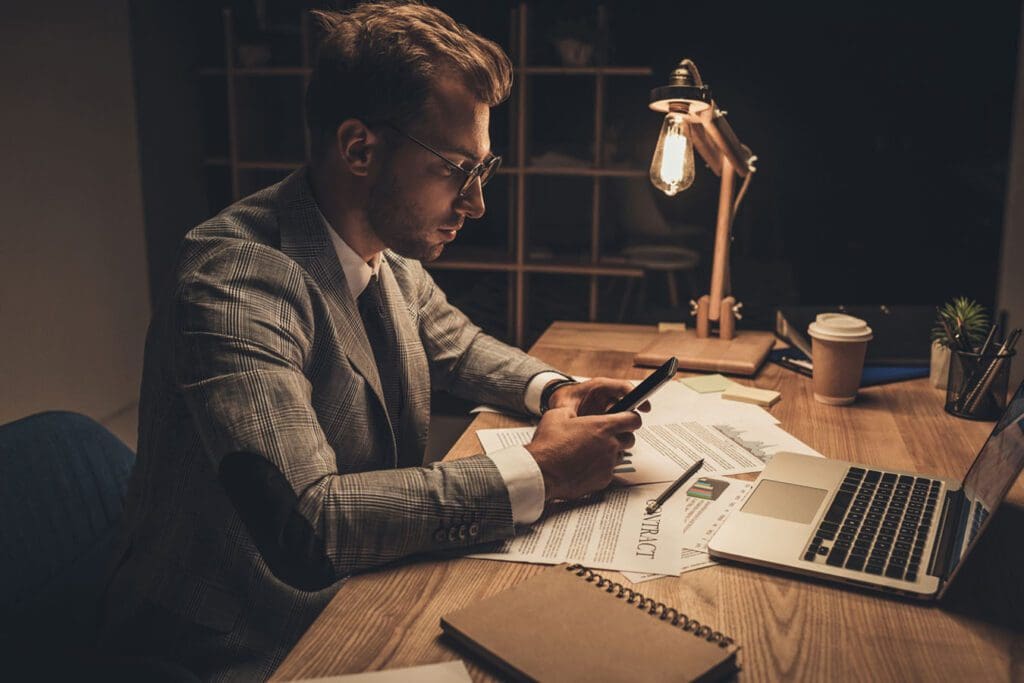 young professional using smartphone at workplace on a late night